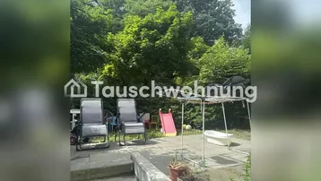 Gepflasterte Terrasse mit Gartenmöbeln, Spielbereich und üppigem Grün im Hintergrund.