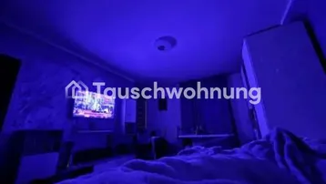 Schlafzimmer mit blauer Beleuchtung, Fernseher an der Wand und Dachschräge.