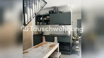 Moderne Küche mit dunkelgrünen Schränken, integriertem Backofen und einer Treppe im offenen Wohnbereich.