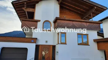 Traditionelles Haus mit weißer Fassade, Holzbalkonen und Satteldach.