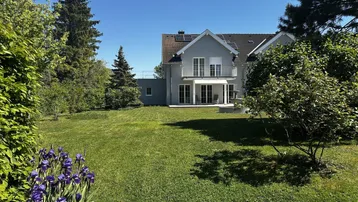 Gepflegter großer Garten mit Rasenfläche und blühenden Blumen vor der Hausfassade.
