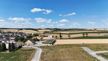 Weitläufige Luftaufnahme der ländlichen Umgebung mit Feldern, Windrädern und einem Dorf.