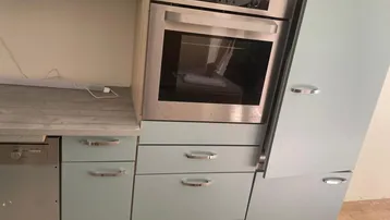 Einbauküche mit hellem Ofen und pastellblauen Schränken, teilweise installiert und funktionsfähig.