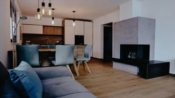 Offener Wohn- und Essbereich mit moderner Küche, Kamin und Holzboden.