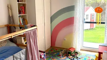 Kinderzimmer mit Etagenbett, farbenfroher Wandgestaltung und Zugang zum Garten.