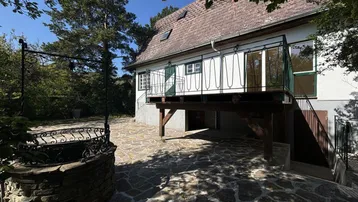 Steinpflasterter Terrassenbereich mit einem dekorativen Brunnen und Zugang zum Haus.