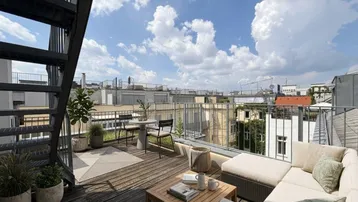 Möblierte Dachterrasse mit Lounge-Bereich, Pflanzen und weitem Blick über die Stadt.