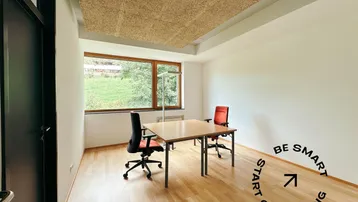 Modernes Büro mit Holzboden, großem Fenster und Blick ins Grüne, ideal für Coworking-Arbeitsplätze.