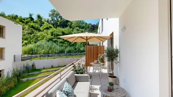 Helles Balkon mit bequemen Gartenmöbeln und Blick ins Grüne, ideal zum Entspannen im Freien.