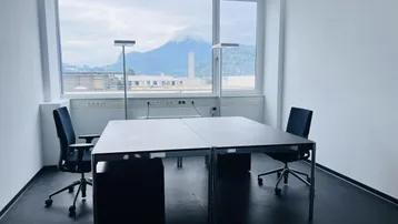 Modernes Büro mit zwei Arbeitsplätzen, großen Fenstern und Bergblick.