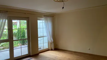 Helles Wohnzimmer mit Parkettboden, Stuckdecke und direktem Zugang zur Terrasse.