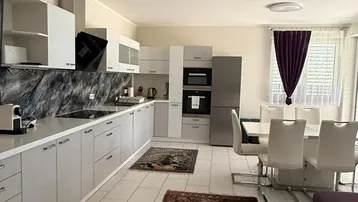 Moderne offene Küche mit Essbereich, weißen Fliesen und dunklen Teppichen.