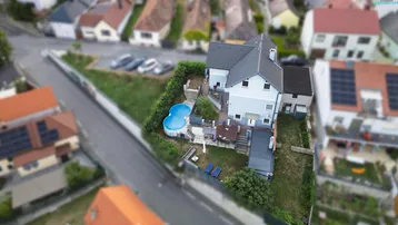 Luftaufnahme eines Einfamilienhauses mit Garten, Pool und umliegender Nachbarschaft.