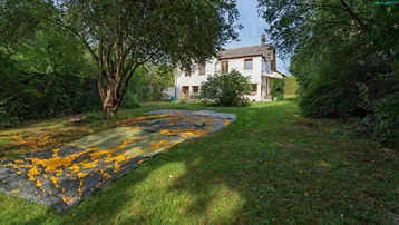 Großer Garten mit Rasenfläche und Obstbäumen, im Hintergrund das weiße Wohnhaus.
