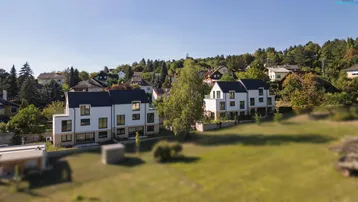 Weitläufige Ansicht der modernen Wohnanlage in grüner Hügellandschaft.