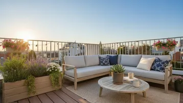 Gemütliche Dachterrasse mit bequemen Loungemöbeln, Pflanzen und Blick auf die Stadt bei Sonnenuntergang.