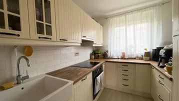 Funktionale Küche mit weißen Schränken, Holz-Arbeitsplatten und integriertem Backofen.