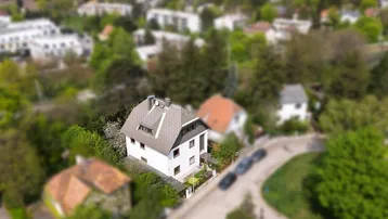 Luftaufnahme eines Einfamilienhauses mit Satteldach und umgebender grüner Landschaft.