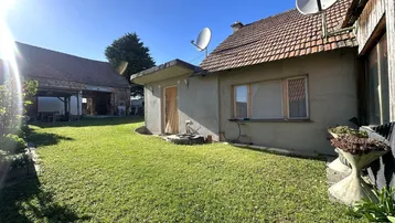 Sonnige Rasenfläche im Garten hinter dem Haus mit Satellitenschüsseln auf dem Dach.