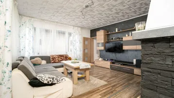Wohnzimmer mit Ecksofa, Holzboden, TV-Wand und dekorativem Kamin.