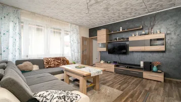 Gemütliches Wohnzimmer mit großem Ecksofa, Holzboden und moderner TV-Wand.