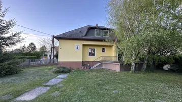 Seitenansicht des Hauses mit großem Garten und altem Baumbestand bei Sonnenuntergang.