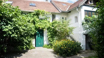 Charmantes Haus mit üppiger Begrünung, Kletterpflanzen und einem grünen Eingangstor.