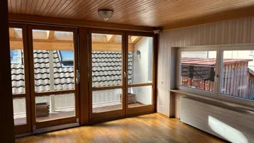 Helles Zimmer mit Holzboden und Zugang zu einem überdachten Balkon, ideal für entspannte Stunden.