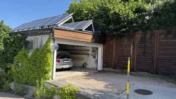 Garage mit Photovoltaikanlage auf dem Dach und Stellplatz für ein Fahrzeug.