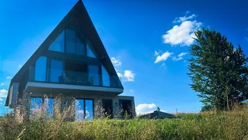 Modernes A-Rahmen-Haus mit großer Glasfassade und weitem Blick in die Natur.