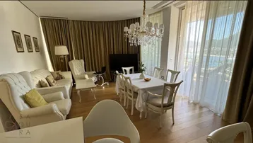 Elegantes Wohn- und Esszimmer mit klassischer Einrichtung, Kronleuchter und Blick auf das Meer.