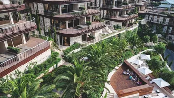 Luxuriöse Apartmentgebäude mit Terrassen, umgeben von üppiger Vegetation und einem stilvollen Außenbereich.