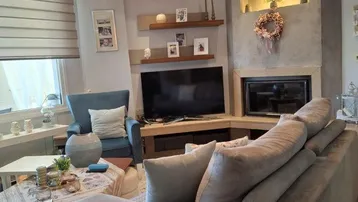 Modernes Wohnzimmer mit integriertem Kamin, Fernseher und bequemer Sitzecke.