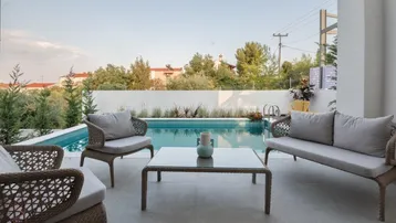 Moderne Terrasse mit bequemen Loungemöbeln und einem erfrischenden Pool, umgeben von grüner Bepflanzung.