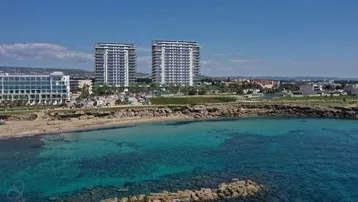 Panoramablick auf moderne Hochhäuser am Meer mit klarem blauen Wasser und Sandstrand.