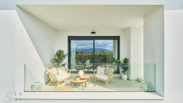 Gemütliche Loggia mit Rattanmöbeln und weitem Blick auf die bergige Landschaft.