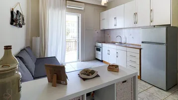 Heller Wohnbereich mit integrierter Küchenzeile, Sofa und Zugang zum Balkon.