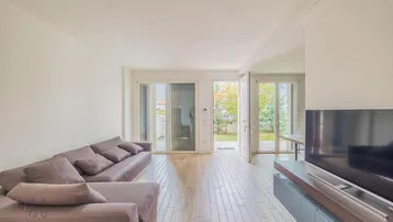 Helles Wohnzimmer mit großem Sofa, TV-Möbel und direktem Zugang zum Garten.
