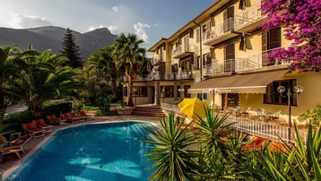 Großzügiger Außenbereich mit Swimmingpool, Palmen und einem Hotelgebäude im Hintergrund.