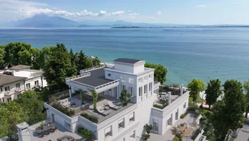 Luxuriöses Gebäude am Seeufer mit mehreren Terrassen und Panoramablick auf den See und die Berge.