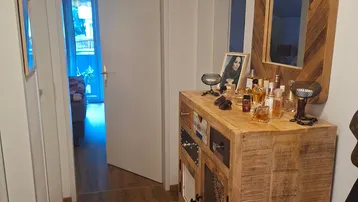 Heller Eingangsbereich mit rustikalem Holzschrank, großem Spiegel und einem dekorativen Kuhfellteppich.