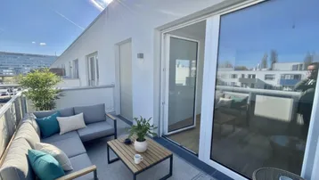 Sonniger Balkon mit modernen Outdoor-Möbeln und Blick auf die Umgebung.