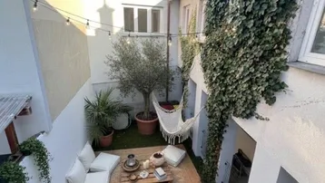 Gemütlicher Innenhof mit Lounge-Möbeln, Hängematte und Pflanzen, ideal zum Entspannen im Freien.