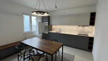Moderne Küche mit grauen und weißen Schränken, Induktionskochfeld und Essbereich am Fenster.