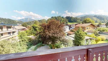 Weitläufiger Ausblick von einem Balkon auf die umliegende Berglandschaft und das Tal.
