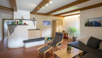 Gemütliches Wohnzimmer mit traditionellem Kachelofen, Holzbalken und rustikalem Charme.