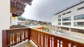 Holzbalkon mit Blick auf umliegende Gebäude und die entfernten Berge.