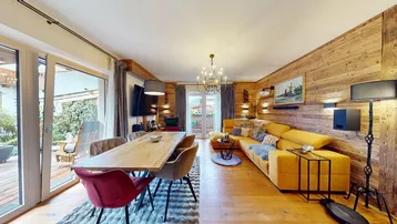 Geräumiger Wohn-Essbereich mit Holzwänden, modernem Sofa und großem Esstisch.