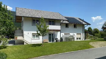 Rückansicht des Hauses mit Photovoltaikanlage auf dem Dach und gepflegtem Garten.