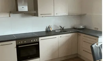Helle Einbauküche mit modernen weißen Schränken, Dunstabzugshaube und Parkettboden.